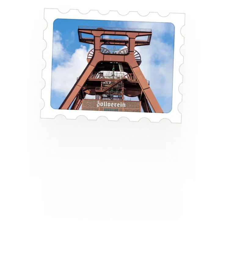 Industrial red steel structure of the Zollverein Coal Mine industrial complex against a partly cloudy blue sky.